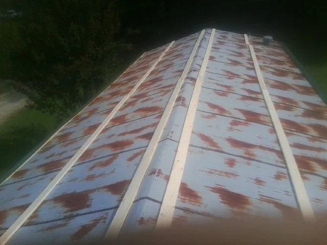 Rusted metal roof panels with new wood purlins before replacement — Storm Damage Roof Repair in Sutton by Roofing Brothers