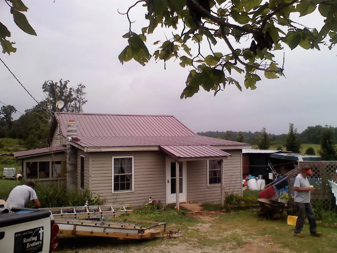Crew finishing a mauve metal roof on a small farmhouse in Sutton