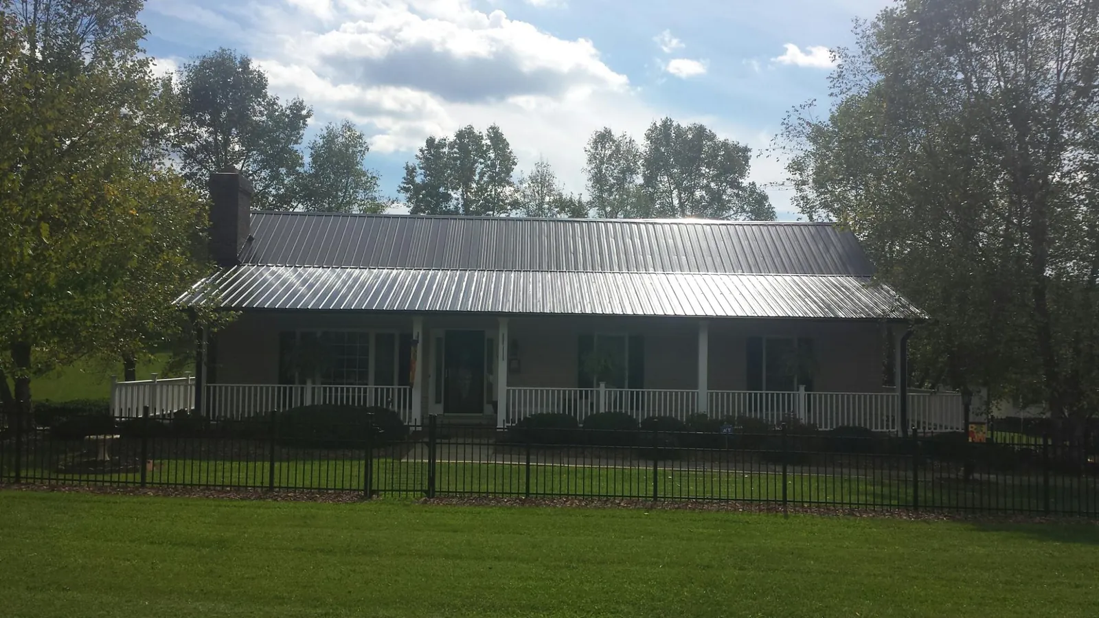 Gray metal roof on a brick ranch with a full width front porch — Gutter Guard Installation work by our crew in Sutton